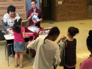 Bonnie Hutson, Savin Rock Community School Family Resource Center staff, left and paraprofessional Gaelle Frazer, right, distribute food packages to students.